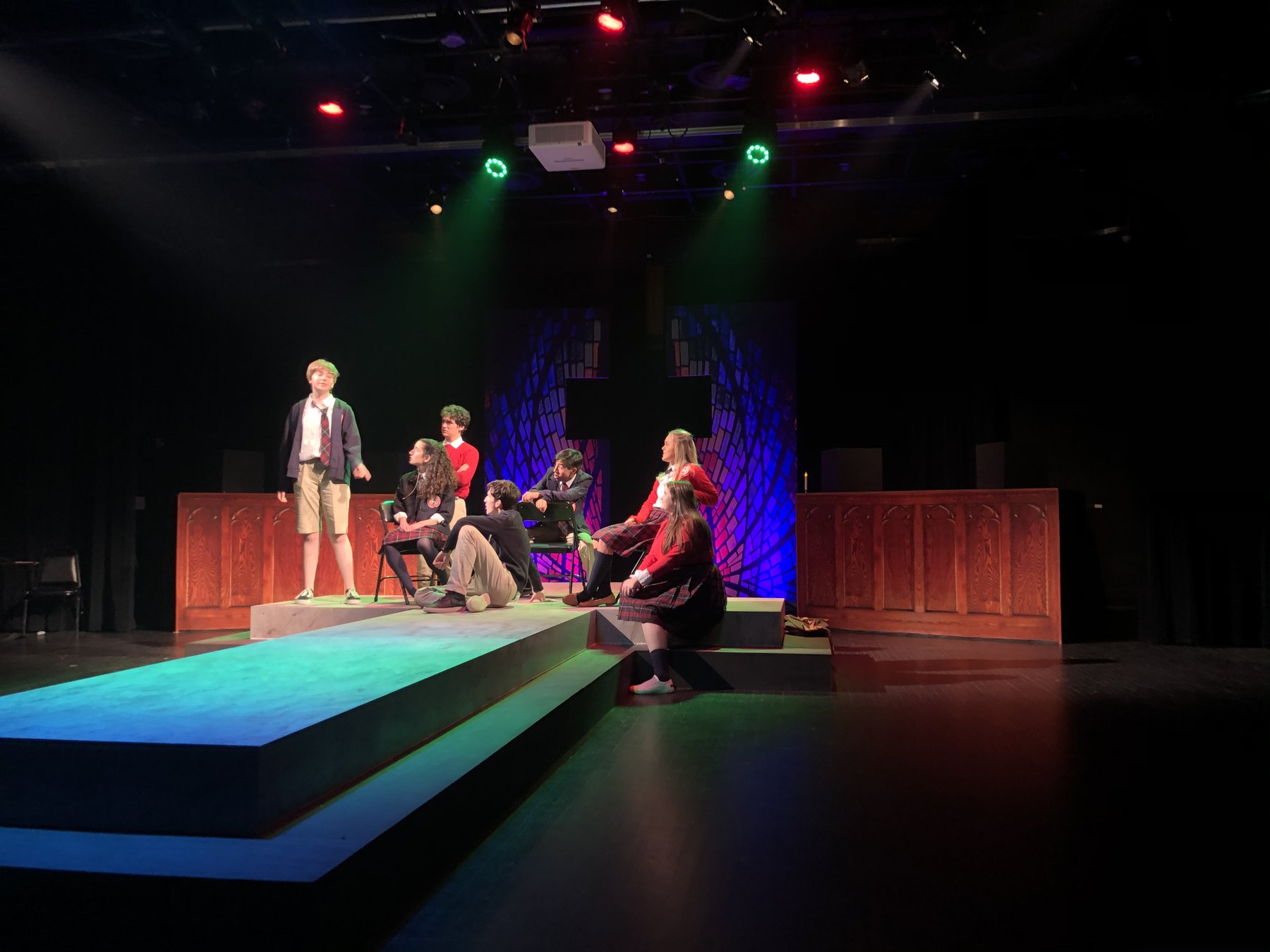 Bare in performance — cast on the cruciform thrust under stage lighting
