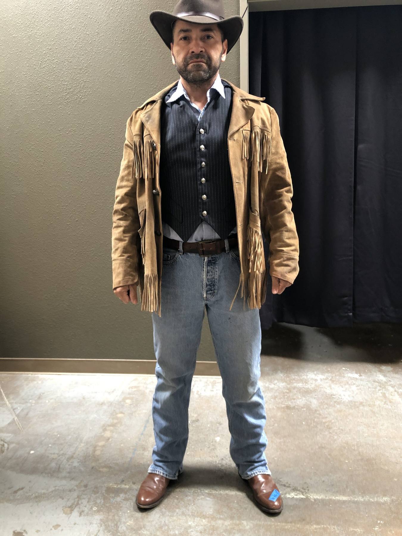 Character fitting — suede fringe jacket, pinstripe vest, jeans, boots, cowboy hat