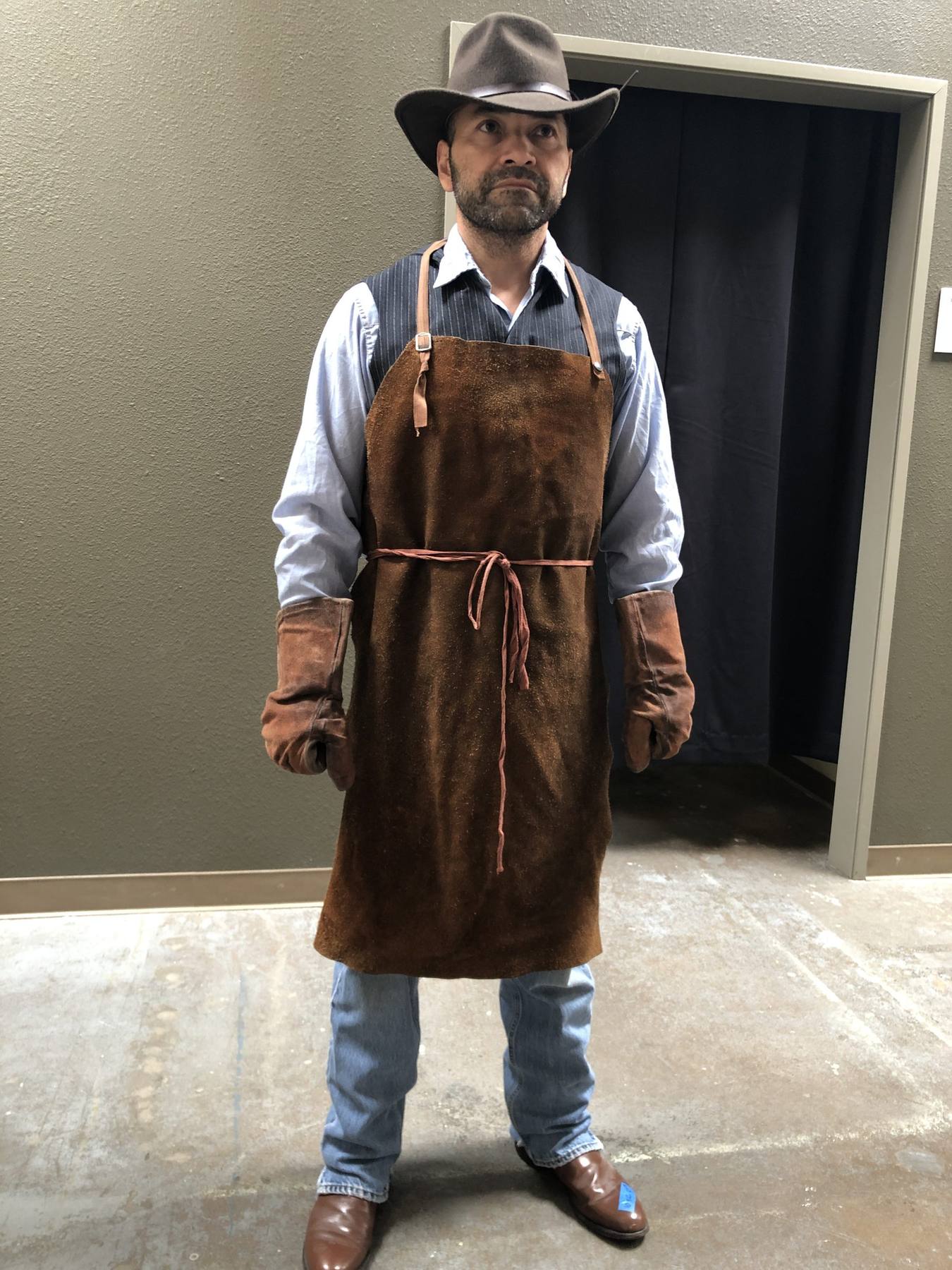 Character fitting — leather work apron over pinstripe vest and shirt