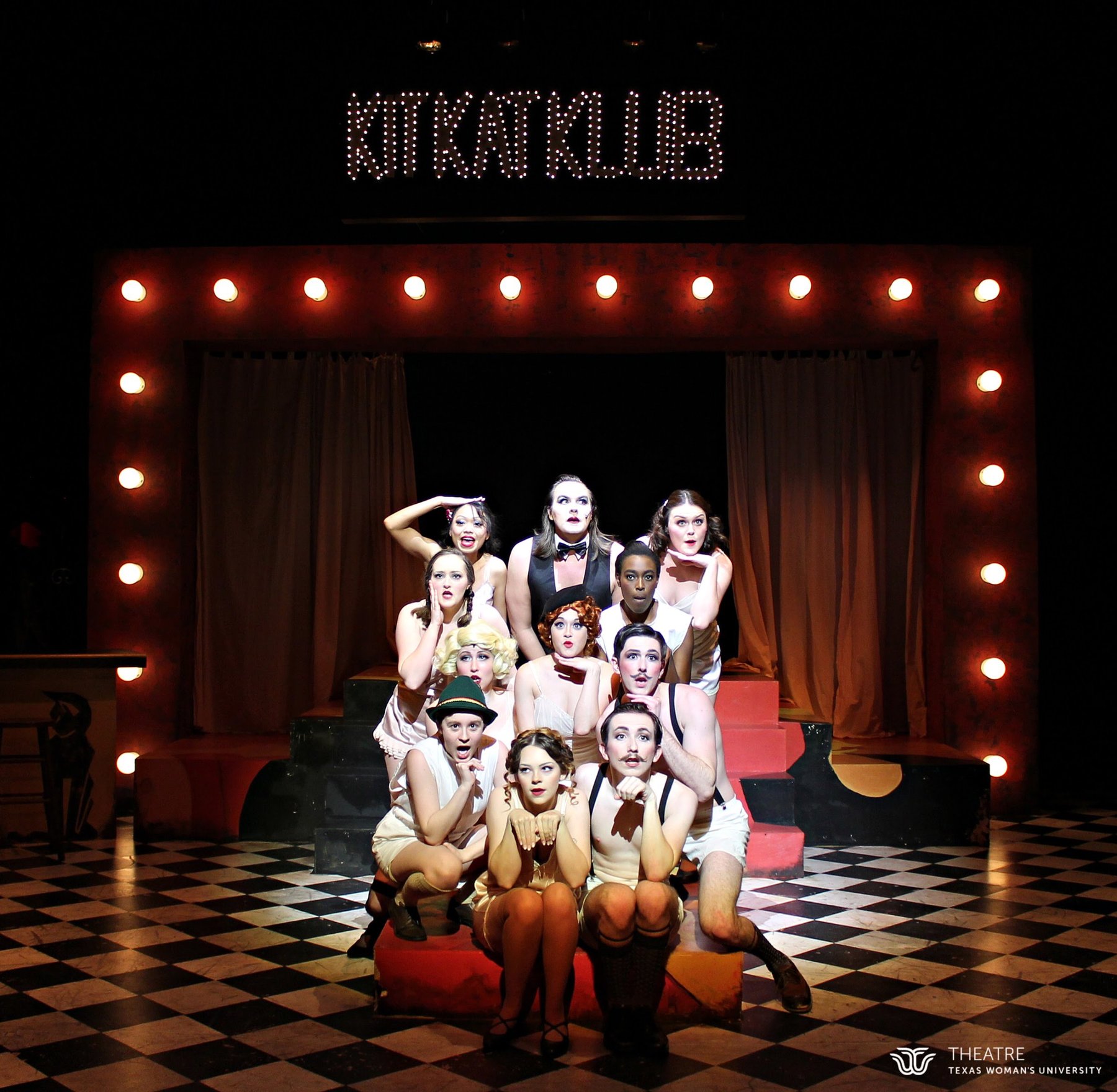 Cabaret — the ensemble in a pyramid pose under warm light