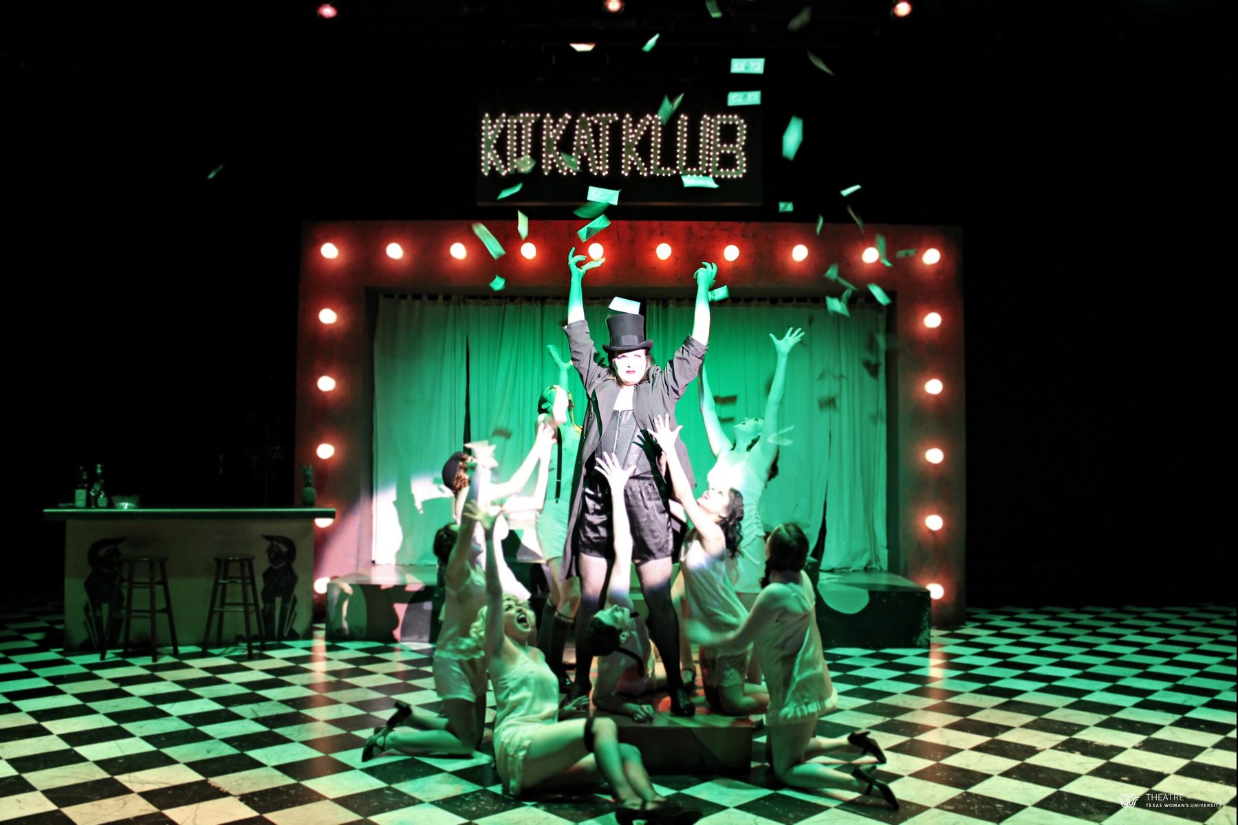 Cabaret — the Emcee tossing money under green light