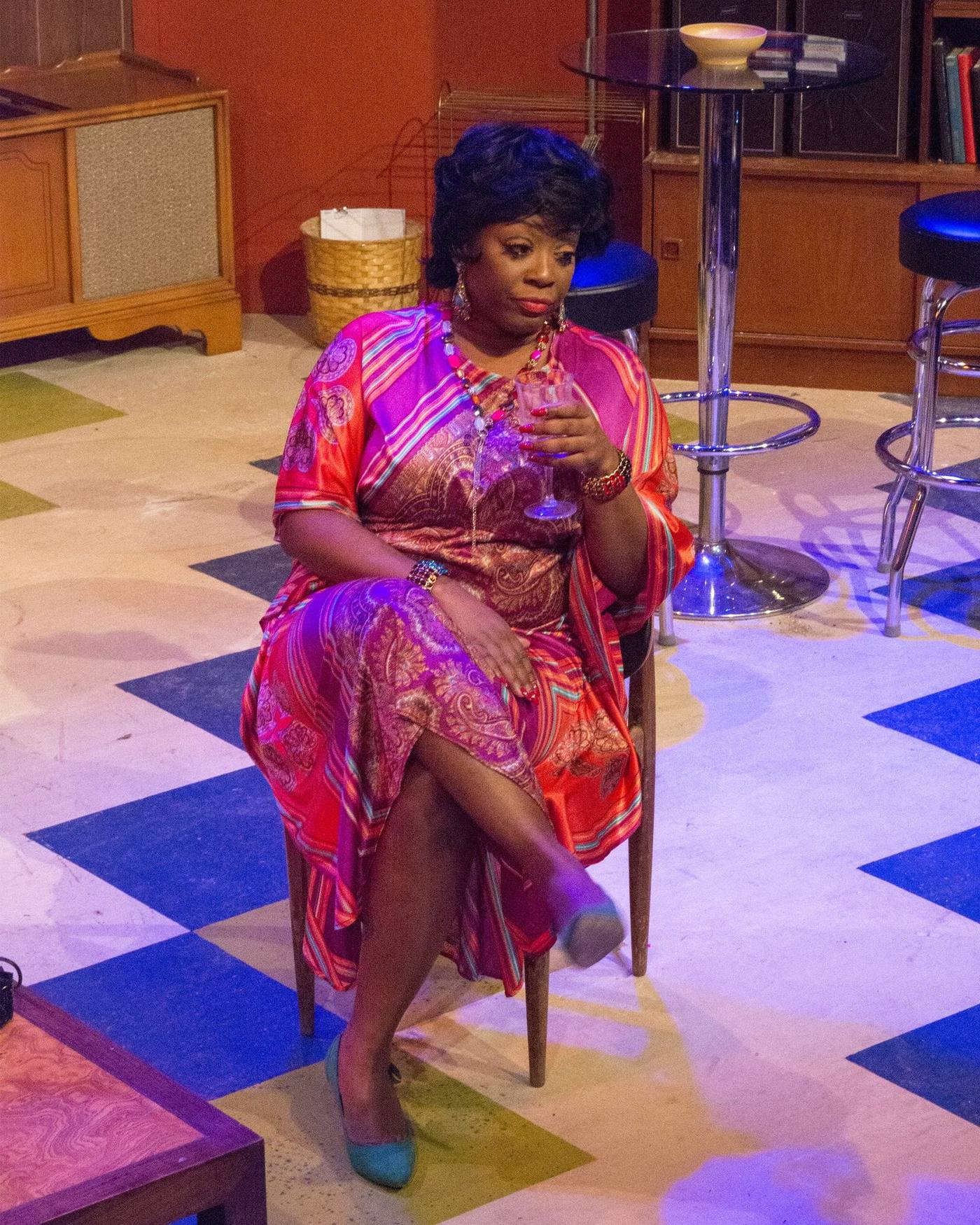 Production photo — woman in paisley kaftan with cocktail