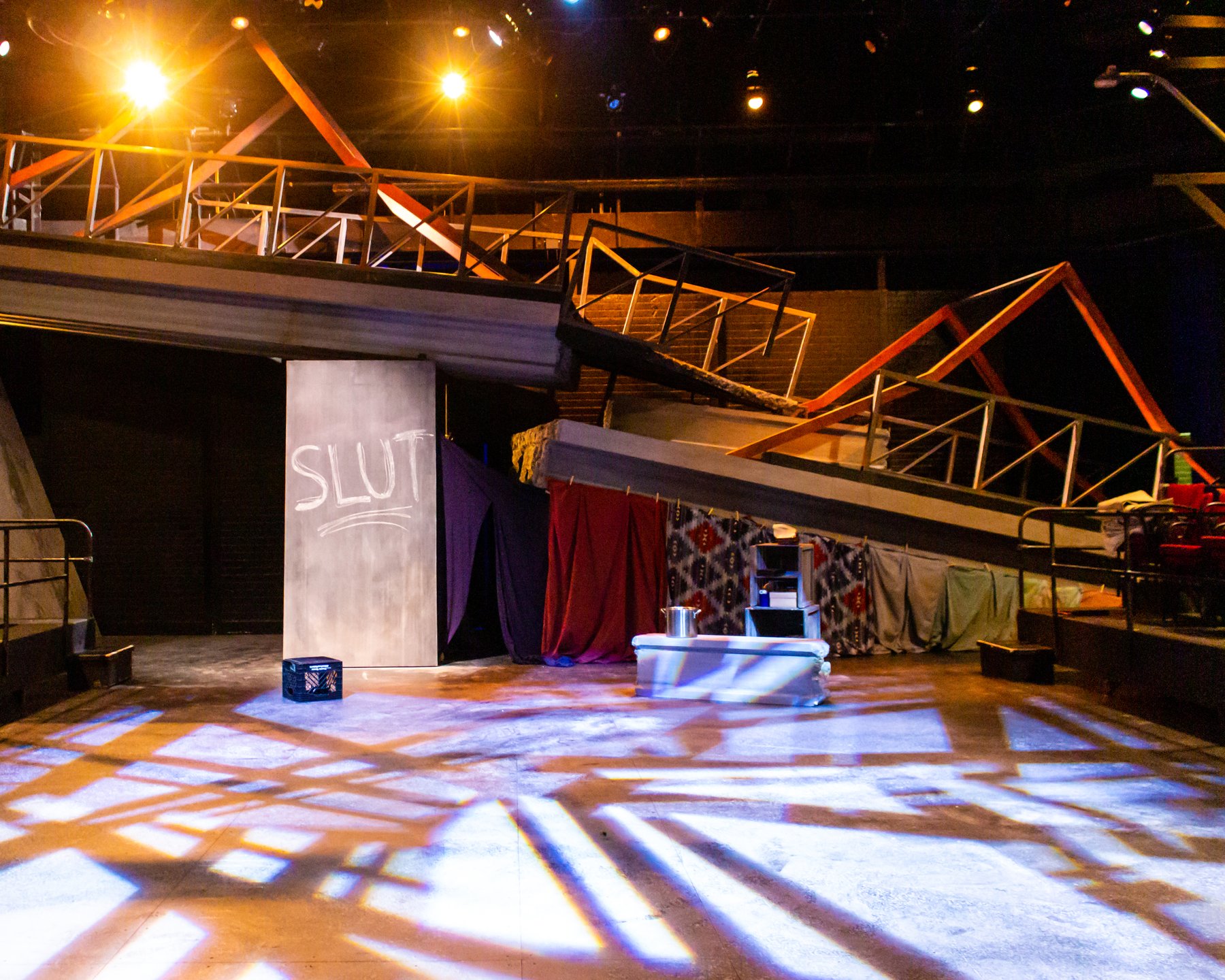 In the Blood — the real broken-bridge set: collapsed overpass spanning the stage under gobo light
