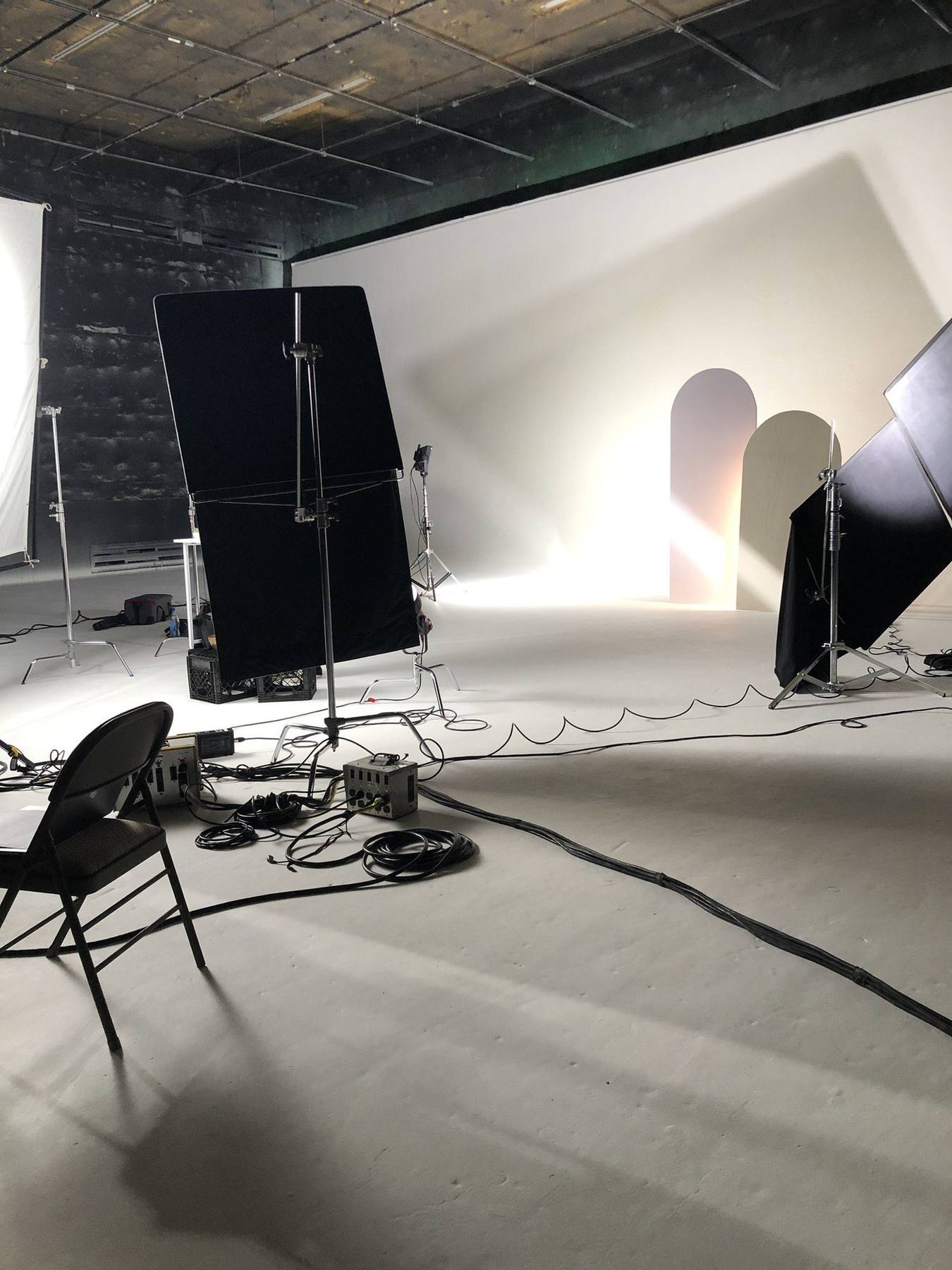 Behind the scenes — wide studio setup with cyc wall, lighting flags and the styled arch backdrop