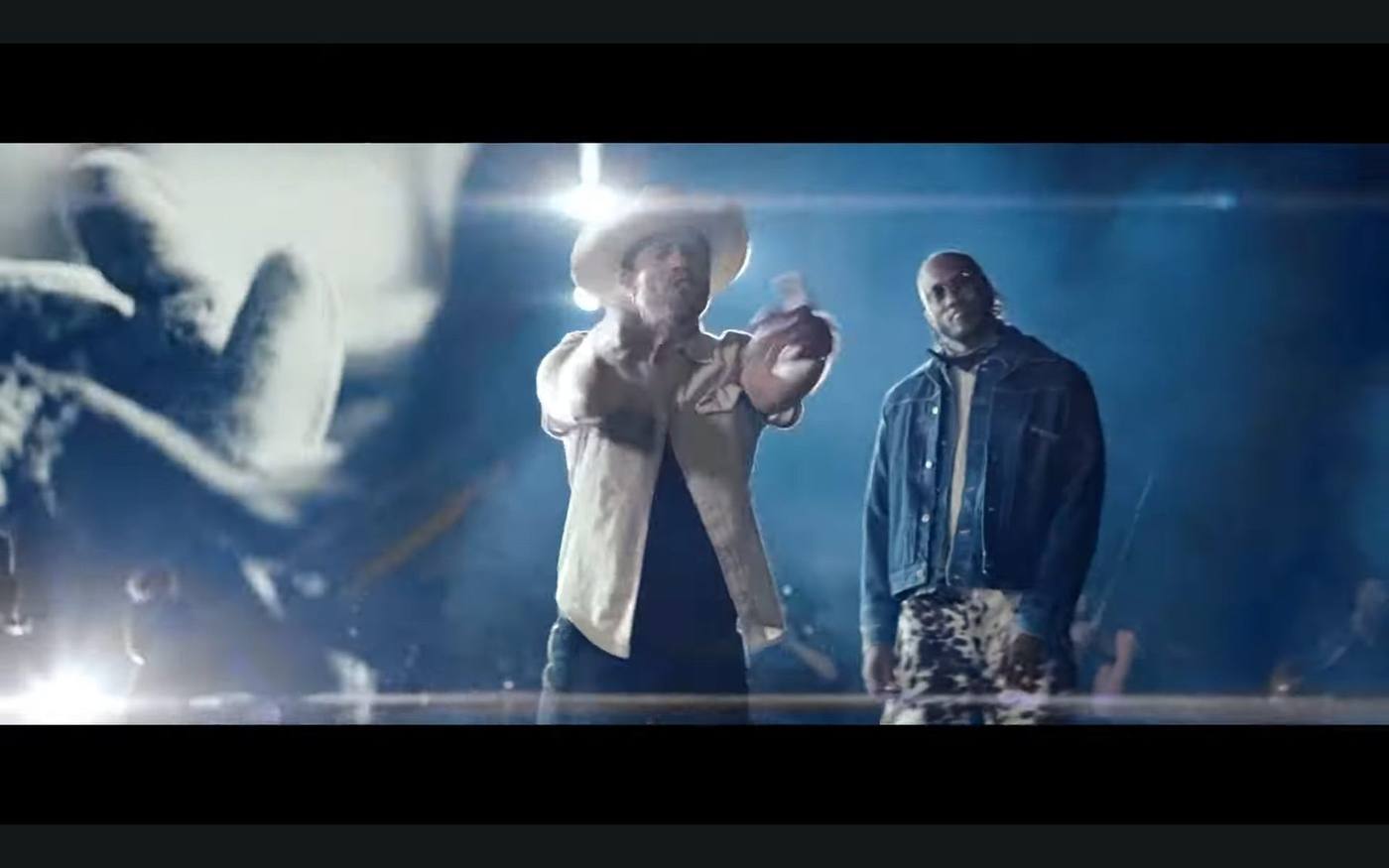Final still — both leads facing camera, country lead with bottle, hip-hop lead beside in denim jacket and printed pants