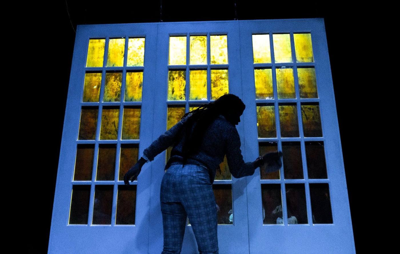 Production — an actor delivering downstage with the company banked behind on the steps