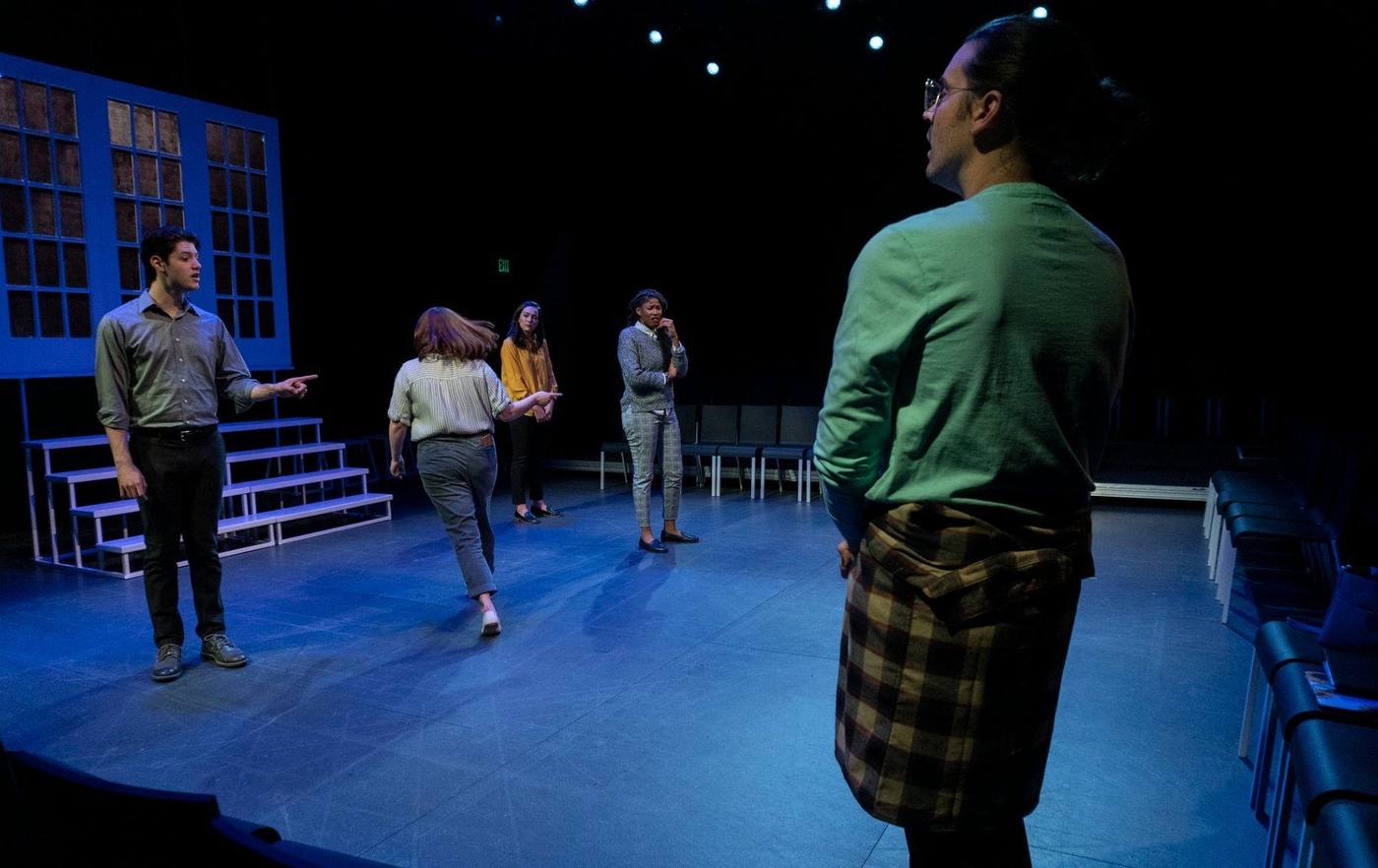 Production — a downstage exchange in front of the step unit, audience visible on three sides