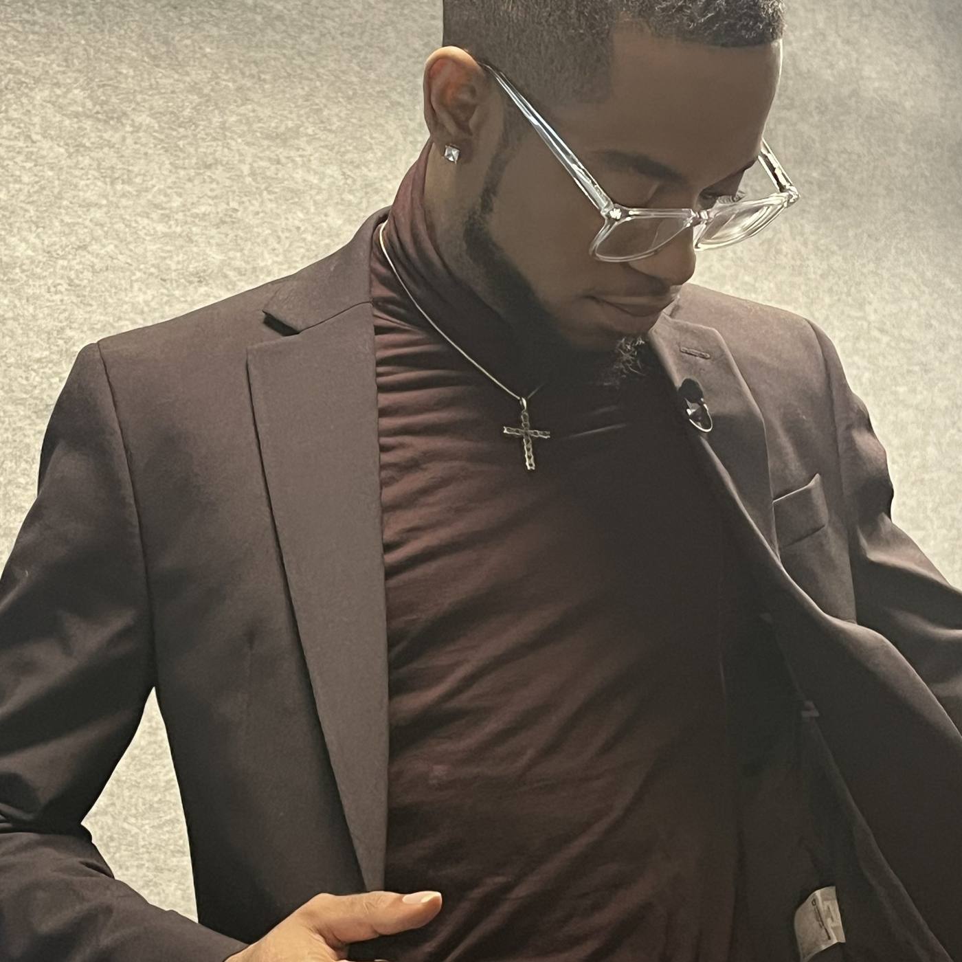 Guest fitting — chocolate suit over turtleneck, clear glasses